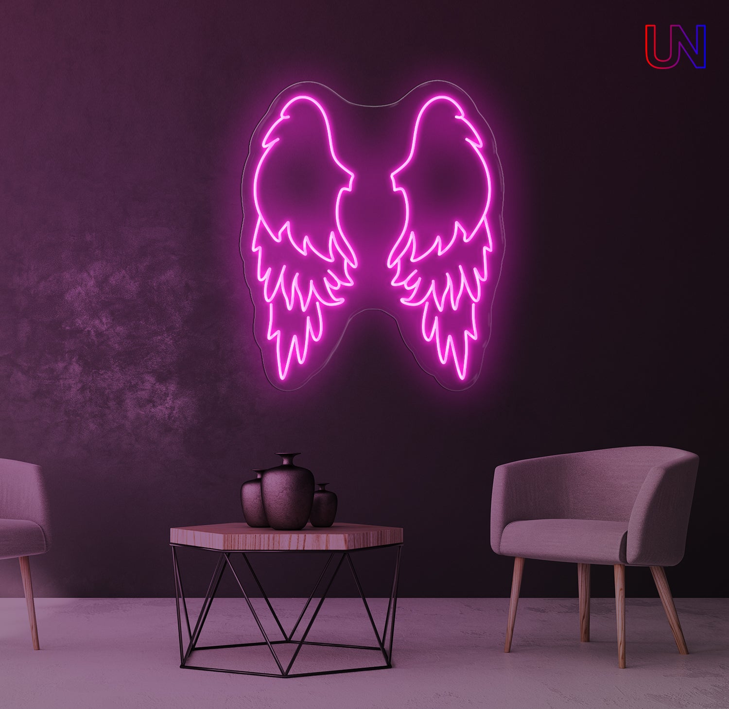 Neon pink angel wings light fixture on a dark purple wall with a table and chairs in the foreground.