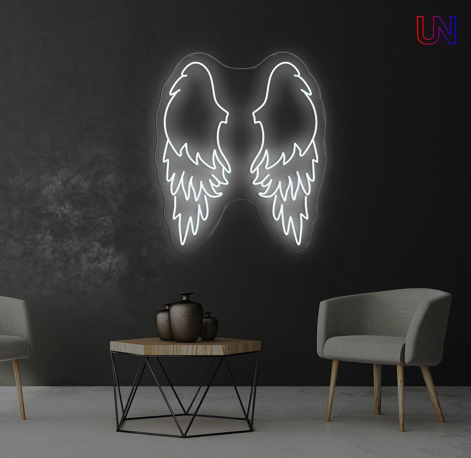 Neon angel wings light fixture on a dark wall with two chairs and a table in the foreground.