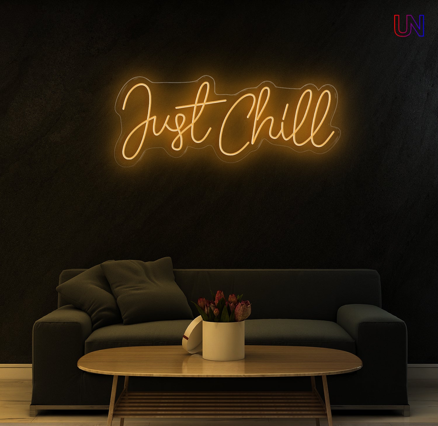 Neon sign reading 'Just Chill' above a dark sofa in a dimly lit room.