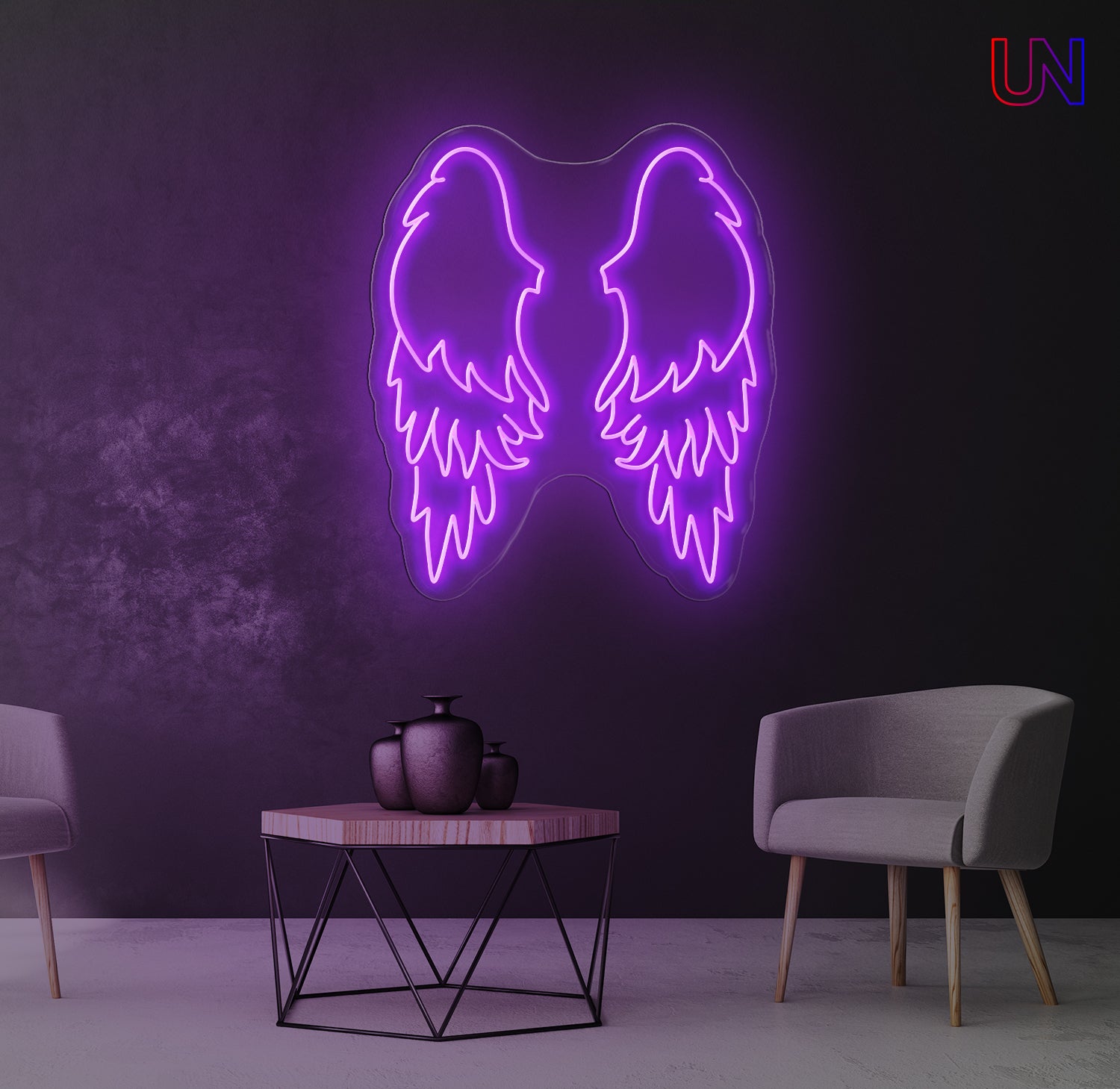 Neon angel wings light fixture on a dark wall with two chairs and a table in the foreground.